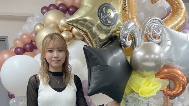 黒と金の星のバルーンの横に佇む30代の女性