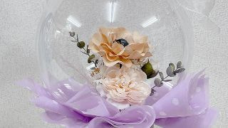 紫色の柔らかなペーパーの上にあるフラワーアレンジが入った透明のバルーン